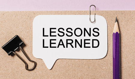 Text LESSONS LEARNED on a white sticker with office stationery background. Flat lay on business, finance and development conceptの写真素材