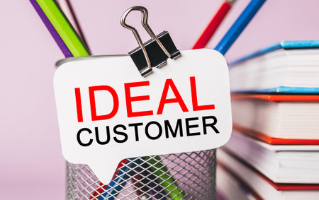 Text IDEAL CUSTOMER on a white sticker with office stationery background. Flat lay on business, finance and development conceptの写真素材