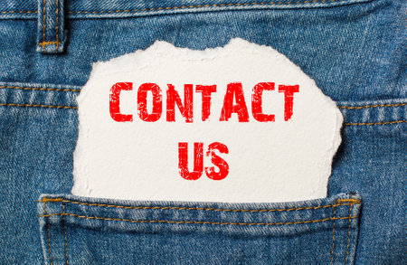 Contact us on white paper in the pocket of blue denim jeansの写真素材