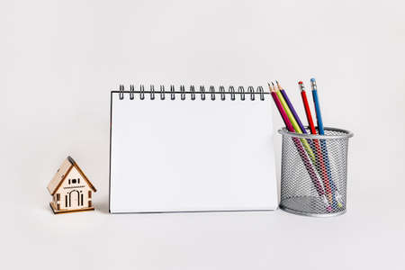 Sweet home. Estimating and paying house tax. Mock up with wooden house, notepad and pencil in copy space white backgroundの写真素材