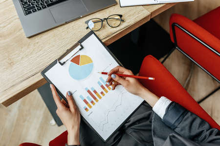 Business woman checks charts and refreshes financial progress. The girl analyzes the business model in the workplace.の写真素材