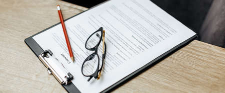 A contract on a wooden work table with glasses and a red pencil. The documents are ready for signing. Business concept. Collaboration agreement.の写真素材