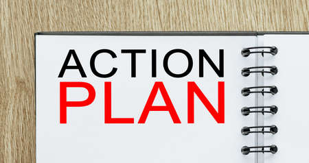 Notepad with text ACTION PLAN on wooden deskt. Business and finance conceptの写真素材