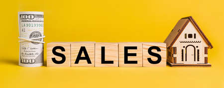 SALES with house miniature model and money on a yellow background. The concept of business, finance, credit, tax , real estate, home, housingの写真素材