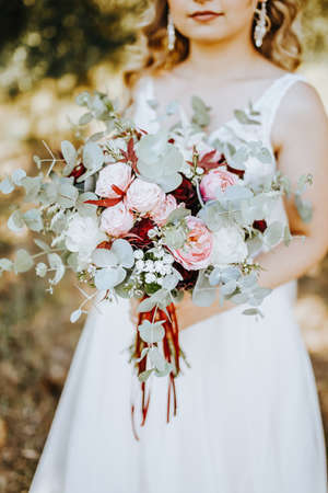 Bride holding wedding bouquet with red and pink flowersの写真素材