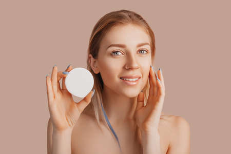 Girl make face beauty masks. Anti-wrinkle cream for the freshness of the skin around the eyes. Woman take care of youthful skin. Model laughing and having fun in spa on pink backgroundの写真素材