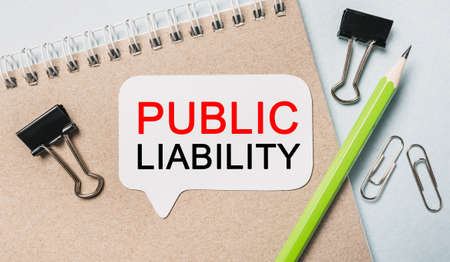 Text PUBLIC LIABILITY on a white sticker with office stationery background. Flat lay on business, finance and development conceptの写真素材