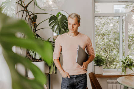Man businessman with laptop in workspace in eco cafe with plantsの写真素材