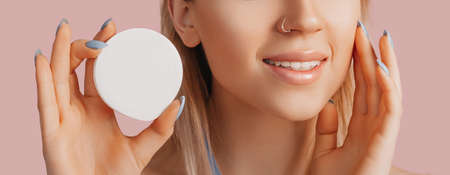 Girl make face beauty masks. Anti-wrinkle cream for the freshness of the skin around the eyes. Woman take care of youthful skin. Model laughing and having fun in spa on pink backgroundの写真素材