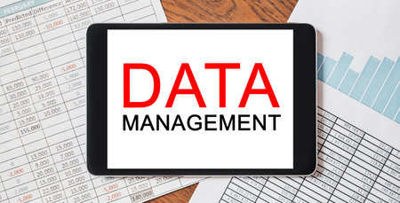 Tablet with text DATA MANAGEMENT on your desktop with documents, reports and graphs. Business and finance conceptの写真素材