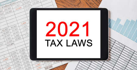 Tablet with text 2021 tax laws on your desktop with documents, reports and graphs. Business and finance conceptの写真素材