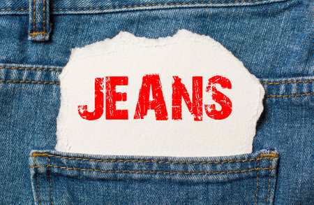 JEANS on white paper in the pocket of blue denim jeansの写真素材