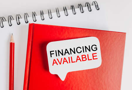 Text Financing Available on a white sticker with office stationery background. Flat lay on business, finance and development conceptの写真素材