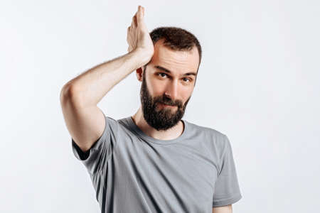 Portrait of cheerful young man smiling while looking at camera holding hands out to sides on white background with space for advertising mock upの写真素材
