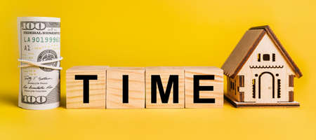 TIME with house miniature model and money on a yellow background. The concept of business, finance, credit, tax , real estate, home, housingの写真素材