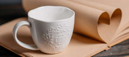 Heart made from book sheets with a cup, love and valentine concept on a wooden tableの写真素材