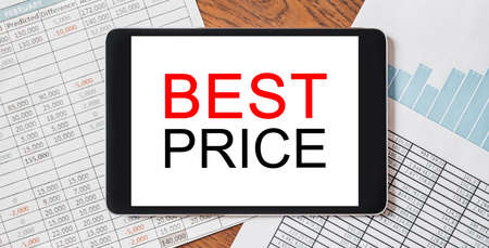 Tablet with text BEST PRICE on your desktop with documents, reports and graphs. Business and finance conceptの写真素材