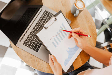 Business man checks information in charts in office near laptopの写真素材