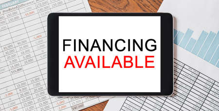 Tablet with text Financing Available on your desktop with documents, reports and graphs. Business and finance conceptの写真素材