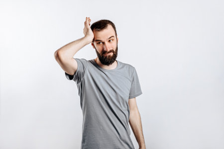 Portrait of cheerful young man smiling while looking at camera holding hands out to sides on white background with space for advertising mock upの写真素材