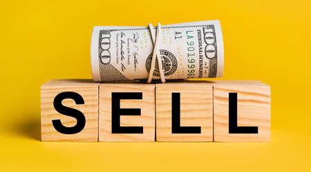 SELL with money on a yellow background. The concept of business, finance, credit, income, savings, investments, exchange, taxの写真素材