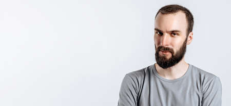 Portrait of a handsome brutal brunette serious man on a white background with crossed arms. The person will soon become the owner of a startup business.の写真素材
