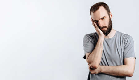 Portrait of cheerful young man smiling while looking at camera holding hands out to sides on white background with space for advertising mock upの写真素材