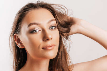 Beautiful young girl smiling and posing looking at the camera on a white isolated background. Positive brunette woman. Kind look. Beauty face.の写真素材