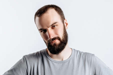 Portrait of cheerful young man smiling while looking at camera holding hands out to sides on white background with space for advertising mock upの写真素材