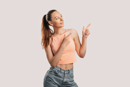 Portrait of a smiling girl pointing finger to the side at on a white isolated background. Positive woman points to an idea, a place for advertisingの写真素材