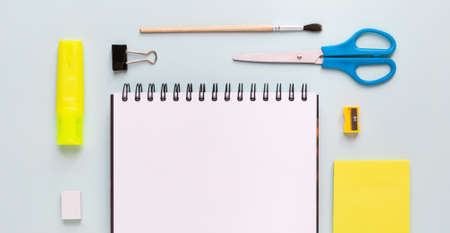 Top view of modern white blue office desktop with school supplies and stationery on table around...