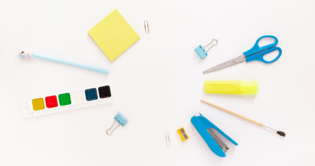 Top view of modern white blue office desktop with school supplies and stationery on table around...