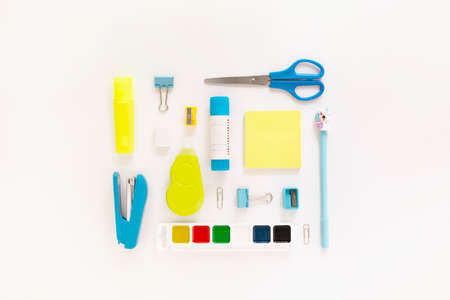 Top view of modern white, blue, yellow office desktop with school supplies and stationery on table...