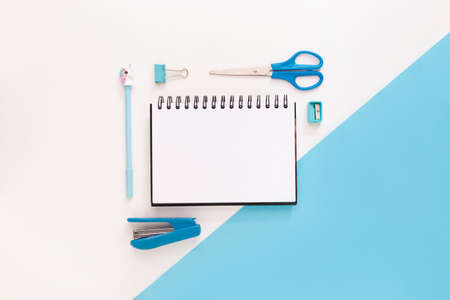 Top view of modern white blue office desktop with school supplies and stationery on table around empty space for text. Back to school concept flat lay with mockupの写真素材