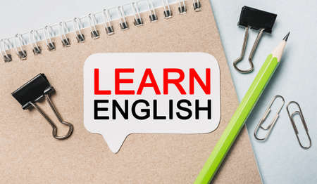 Text Learn ENGLISH on a white sticker with office stationery background. Flat lay on business, finance and development conceptの写真素材