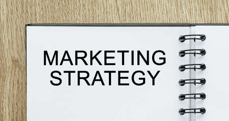 Notepad with text Marketing Strategy on wooden deskt. Business and finance conceptの写真素材