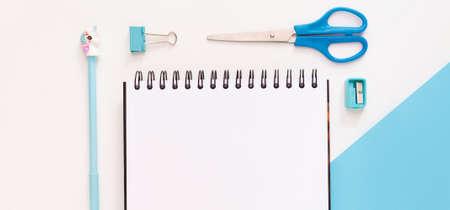 Top view of modern white blue office desktop with school supplies and stationery on table around empty space for text. Back to school concept flat lay with mockupの写真素材