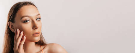 Beautiful young girl smiling and posing looking at the camera on a white isolated background. Positive brunette woman. Kind look. Beauty face.の写真素材