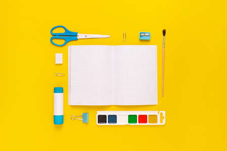 Top view of modern white, blue, yellow office desktop with school supplies and stationery on table...