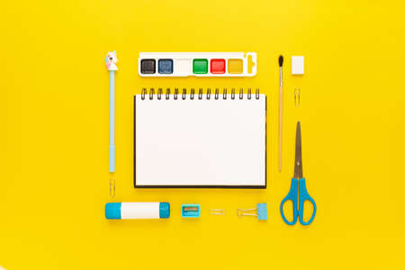 Top view of modern white, blue, yellow office desktop with school supplies and stationery on table around empty space for text. Back to school concept flat lay with mockupの写真素材