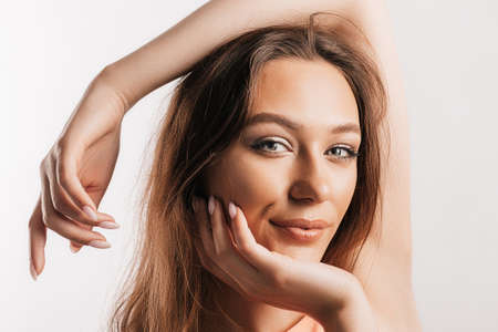 Beautiful young girl smiling and posing looking at the camera on a white isolated background. Positive brunette woman. Kind look. Beauty face.の写真素材