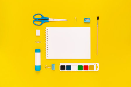 Top view of modern white, blue, yellow office desktop with school supplies and stationery on table around empty space for text. Back to school concept flat lay with mockupの写真素材