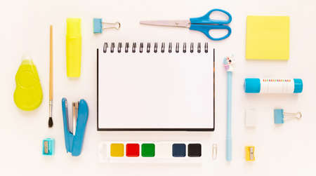 Top view of modern white, blue, yellow office desktop with school supplies and stationery on table around empty space for text. Back to school concept flat lay with mockupの写真素材