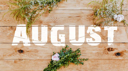 Text august on light wood decorated with plants and flowers. Wooden texture background mockup backgroundの写真素材