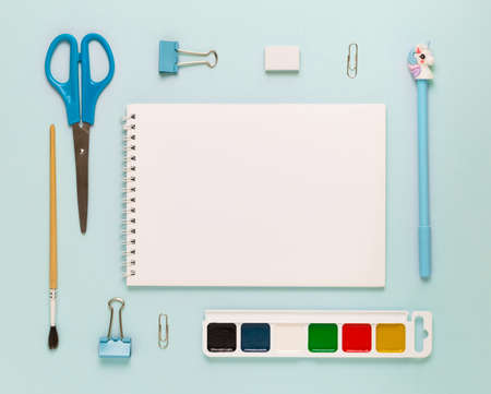 Top view of modern white blue office desktop with school supplies and stationery on table around empty space for text. Back to school concept flat lay with mockupの写真素材