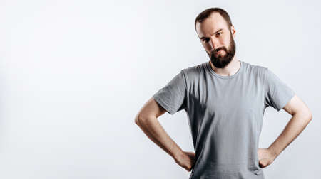 Portrait of cheerful young man smiling while looking at camera holding hands out to sides on white background with space for advertising mock upの写真素材