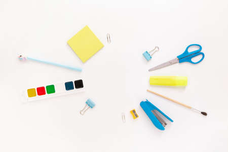 Top view of modern white blue office desktop with school supplies and stationery on table around round empty space for text. Back to school concept flat lay with mockupの写真素材
