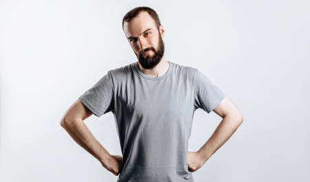 Portrait of cheerful young man smiling while looking at camera holding hands out to sides on white background with space for advertising mock upの写真素材