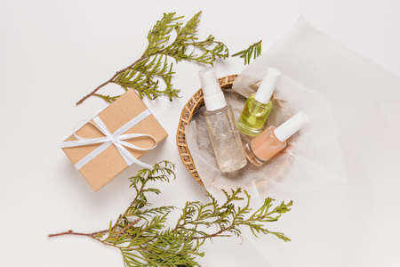Organic cosmetics with plant and gifts for the holiday. Flat lay, top view clear glass pump bottle, brush jar, moisturizing serum jar in a paper basket on a white background. Natural cosmetics SPAの写真素材