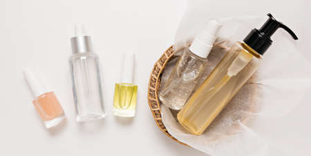 Organic cosmetics packaging design. Flat lay, top view clear glass pump bottle, brush jar, moisturizing serum jar in a paper basket on a white background. Natural cosmetics SPAの写真素材